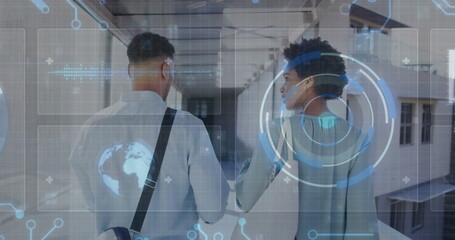 Walking colleagues carrying bag and exploring glass windowed corridor, with holographic interface