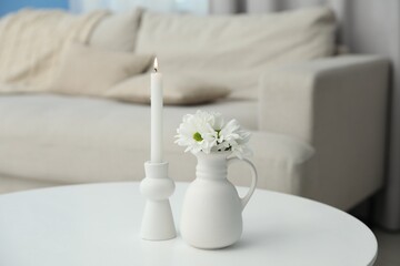 Beautiful chrysanthemum flowers in vase and burning candle on white table indoors
