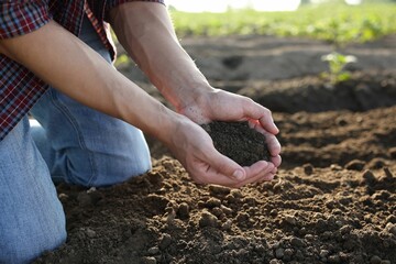Man holding pile of soil in field, closeup