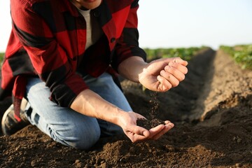 Man with pile of soil in field, closeup