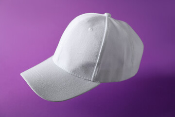 White baseball hat in air on purple background