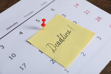 Sticky note with word Deadline and calendar on table, closeup