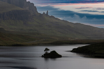 Loch Fada with it's small islet in silhouette during sunrise with the Old Man of Storr famous rock...