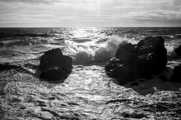 Black and white view of waves crashing against coastal rocks