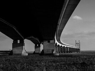 Underside of the Second Severn Bridge in black and white, showcasing its imposing concrete...