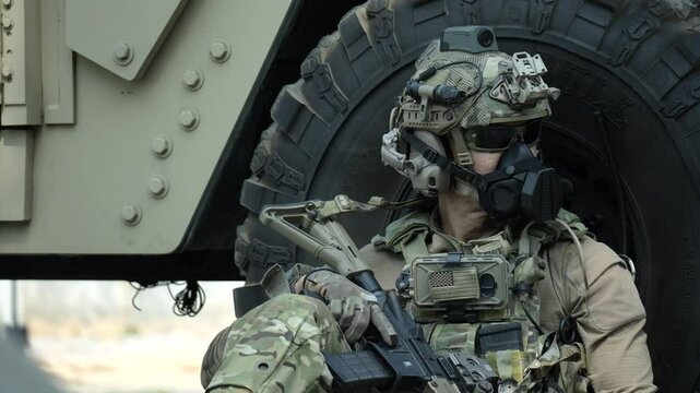 A special forces soldier equipped with a gas mask and advanced combat helmet stands guard by an armored vehicle A concept for CBRN defense and modern warfare readiness