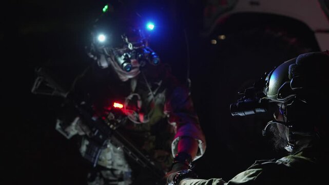 Special forces team gathers at night for a mission briefing, equipped with night vision goggles and tactical gear, ready for a stealth operation under darkness.