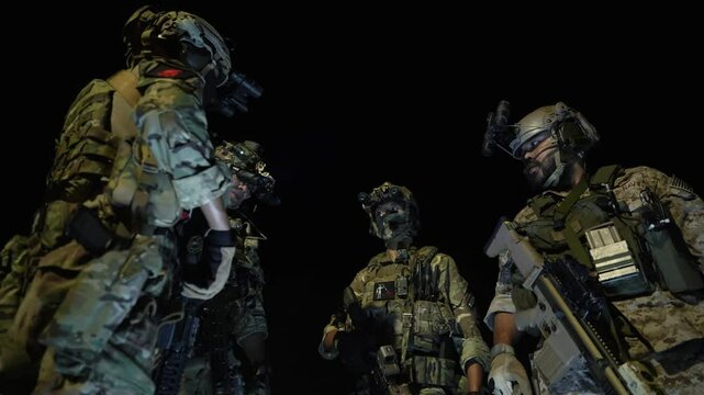 Special forces team gathers at night for a mission briefing, equipped with night vision goggles and tactical gear, ready for a stealth operation under darkness.