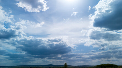 Vast sky filled with fluffy clouds and sunlight filtering through, showcasing natural beauty. Ideal for landscape photography or backgrounds in various projects.