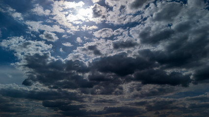 Dramatic clouds covering the sky, with sunlight breaking through. The scene depicts the beauty of nature during the day, showcasing varying shades of gray and blue in the sky.
