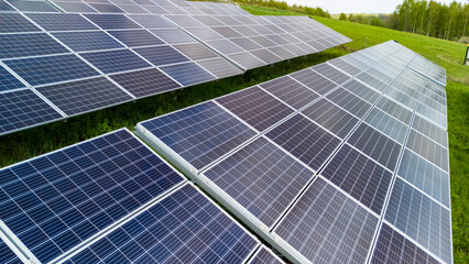 Aerial view of solar panels in a green field, showcasing the shift towards renewable energy...