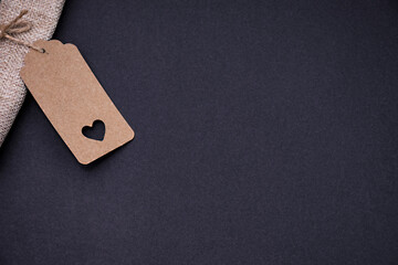 Minimalistic composition featuring a craft gift tag with a heart shaped cutout attached to linen...