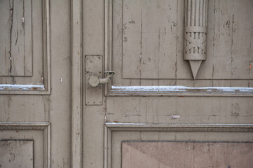 An antique wooden door with chipped handle and symmetrical panel detail
