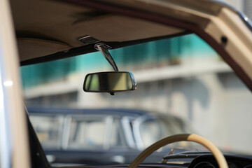The rearview mirror of a classic car has a shiny chrome finish with a simple design, serving as a...