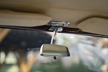 The rearview mirror of a classic car has a shiny chrome finish with a simple design, serving as a...