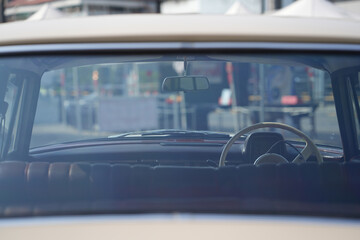 The rearview mirror of a classic car has a shiny chrome finish with a simple design, serving as a...