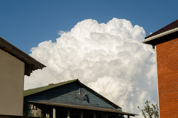 Majestic Cumulus Clouds Towering Over Suburban Homes in Clear Blue Sky During Daytime