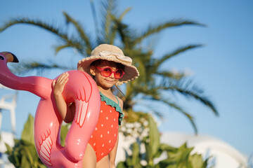 Funny little girl relaxing on summer vacation. The child has fun on the beach. Cute baby in a colorful swimsuit and sunglasses is resting.