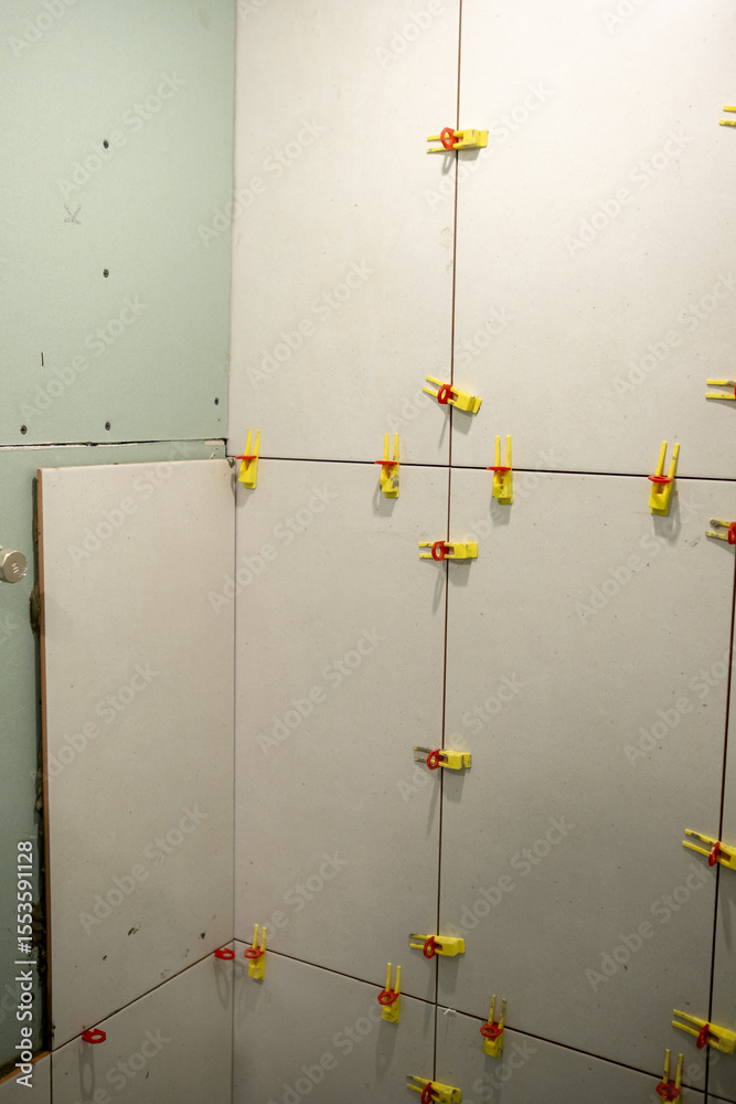 Poster wall installation process with clips used to secure panels in a corner during a renovation project