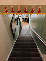 Carpeted descending stairway with green painted walls, wooden handrail and low-clearance beam...