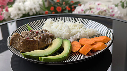 Delicious Meal with Stewed Meat, White Rice, Avocado Slices, and Carrots on a Striped Plate