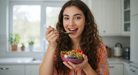 woman eating from a smoothie bowl full of colorful fruits and granola