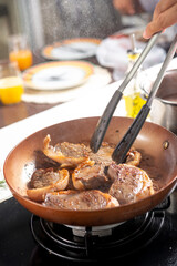 Chef cooking steaks on a frying pan in a restaurant kitchen, beef bourguignon being cooked in a wok pan