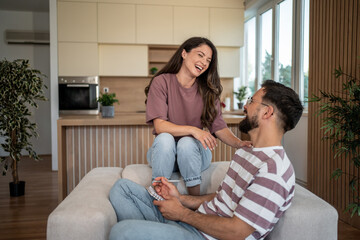 Happy couple laughing together on sofa in modern apartment