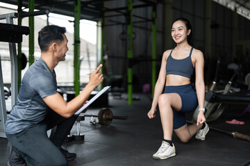 Fitness Coaching and Motivation. A trainer encouraging a woman during lunges in a gym setting.