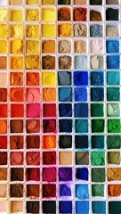 A vibrant and diverse collection of powdered pigments in individual white containers neatly...