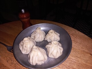 Delicious dumplings on vintage metal plate with pepper mill on wooden table. Khinkali, Georgian cuisine