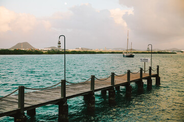 Sunset view from a wooden pier with boats in the distance and a sign warning boats to maintain idle speed