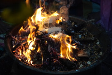Close-up of burning sacred wood and offerings in a fire, part of Hindu rituals for prayer and...
