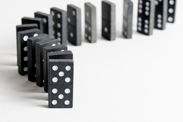 Tessere nere del domino allineate in fila su superficie bianca