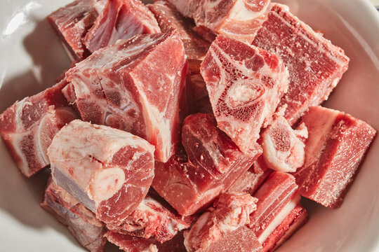 cut up pieces of raw goat meat - Powered by Adobe