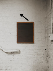 Minimal blank wooden-framed felt letter board mounted on white painted brick wall with black...