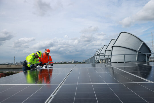 Professional Solor engineering team with green and orange safety jacket and safety hat check and service solar panel on solar roof project , green energy renewable energy