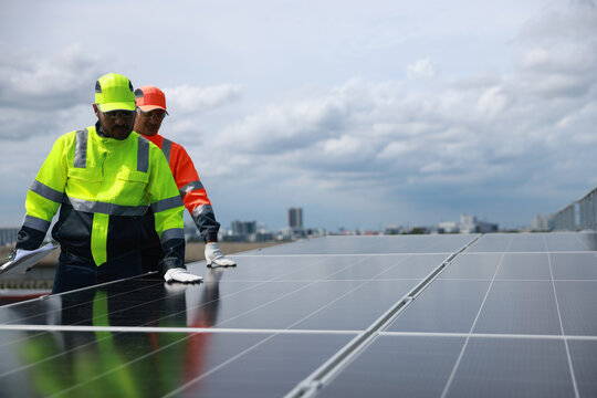 Professional Solor engineering team with green and orange safety jacket and safety hat check and service solar panel on solar roof project , green energy renewable energy