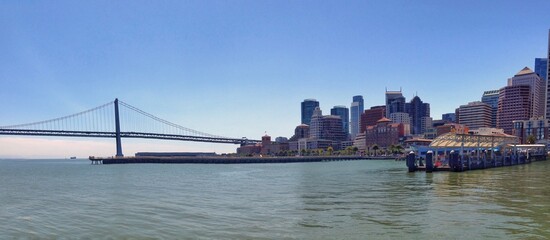 Panoramic view of a city skyline and bridge over water in daylight