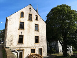 Leerstehendes Haus mit spitzem Giebel und heruntergekommener Fassade in Beige und Naturfarben in...