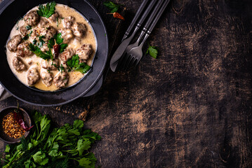 Meatballs in sour cream sauce in a frying pan
