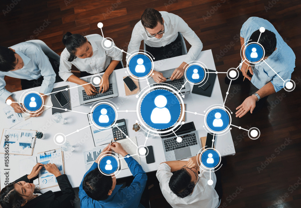 Poster A top-down view of a diverse group of professionals collaborating around a table with laptops, discussing data, and engaging in networking strategies for effective teamwork. Amity