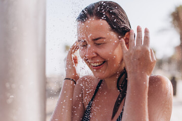 Happy tourist enjoying refreshing shower on beach vacation