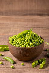 Fresh green peas and pods in a bowl on wooden table. Vegetable healthy food.  