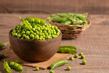 Fresh green peas and pods in a bowl on wooden table. Vegetable healthy food.  
