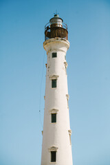 White lighthouse stands tall against a clear blue sky in a coastal landscape