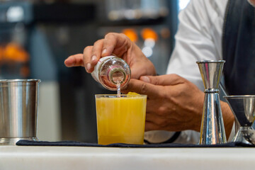 Waiter serving soda on a refreshing orange summer cocktail with ice