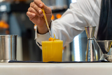Bartender carefully placing orange slice on refreshing cocktail