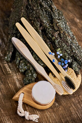 three wooden toothbrushes with natural bristles and a face brush on a background of tree bark, the concept of reducing plastic use, no harmful chemicals