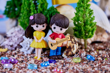 summer romantic doll composition with a girl and a boy who plays her the guitar, at a seaside resort, the concept of the charm of youth and the beginning of a relationship
